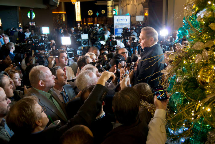 Sports agent Scott Boras talks in front of a giant christmas tree as media members gather in front of him